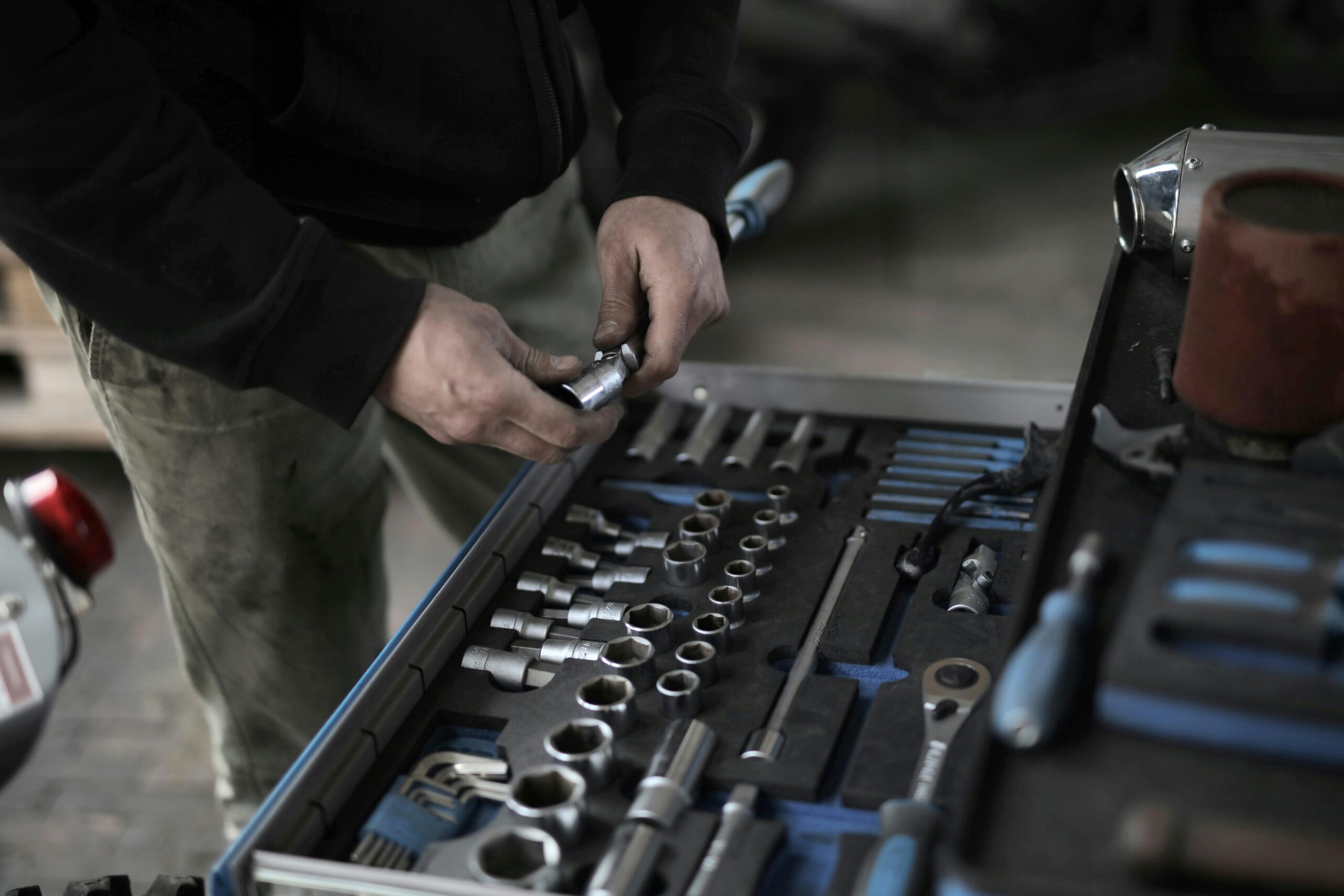 Detail of a mechanic's hands selecting tools from a comprehensive toolset in a workshop.